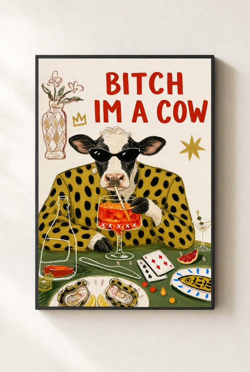Bitch I'm a Cow print, mounted in a black wood frame on a cream wall.