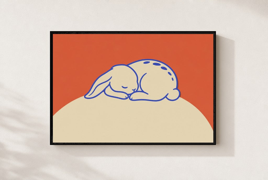 Sleeping Bunny print, mounted in a black wood frame on a cream wall.