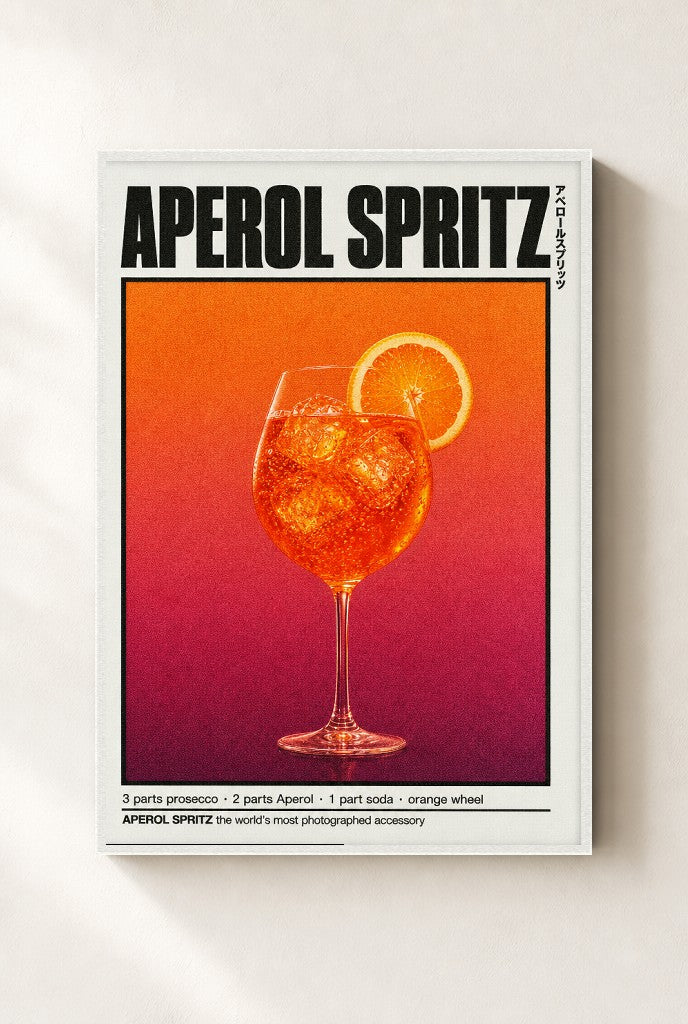 Aperol Spritz print, mounted in a white wood frame on a cream wall.